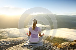 Woman in the top of a cliff meditating doing yoga