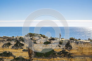 A woman on the top of cliffs at Marinha Beach in Algarve, Portugal