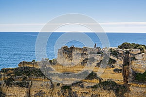 A woman on the top of cliffs at Marinha Beach in Algarve, Portugal