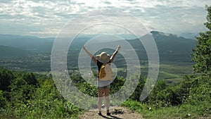 Woman on top of mountain with arms raised looking at view, enjoy vacation trip