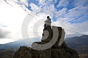 Woman on top of the mountain reaches for the sun