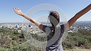 Woman on top of mountian stretching her arms wide open