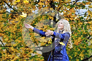 Woman tosses colorful autumn leaves in autumn park photo