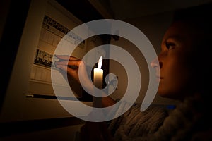 Woman in total darkness investigating fuse box at home during power outage or blackout. No electricity concept photo