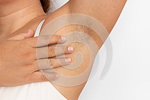 Woman touch hairy underarms with hand closeup, free copy space, beige background. Raised arm with armpit hair. Female