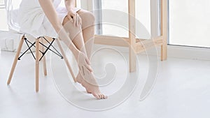 woman touch her smooth and soft skin on legs, enjoy beauty procedures. young asian woman applying cream and lotion touch