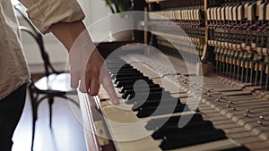 Woman touch keyboard of vintage wooden piano