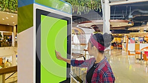 Woman touches a screen of self-ordering kiosk