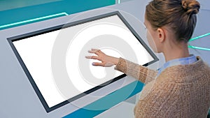 Woman touching blank white display kiosk at exhibition - white screen concept