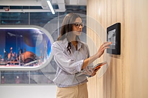 Woman touching control panel on wall in corridor