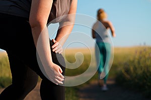 Woman touching her knee, sports injury at jogging