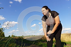 Woman touching her knee, sports injury at jogging