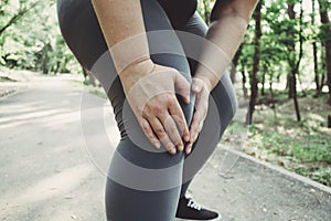 Woman touching her leg, got a knee trauma at outdoor jogging.