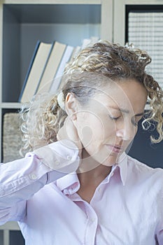 Woman touching her neck at office with headache and pain - stress and tired people in smart working - modern lifestyle concept