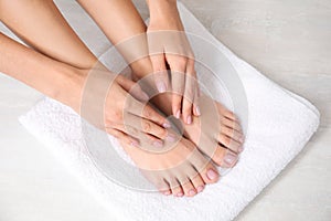 Woman touching her smooth feet on white towel, closeup.