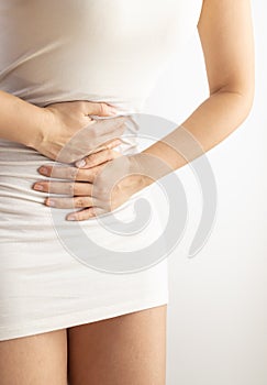 Woman touching her stomach on a white background. Abdominal pain and other stomach ailments.