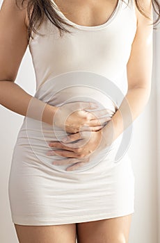 Woman touching her stomach on a white background. Abdominal pain and other stomach ailments.