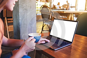 A woman touching on laptop computer touchpad with blank white desktop screen while drinking coffee