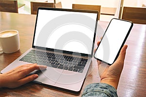 A woman touching on laptop touchpad with blank white desktop screen while using mobile phone