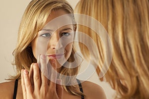 Woman touching mirror while looking at reflection