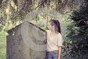 Woman touching a moss overgrown tombstone