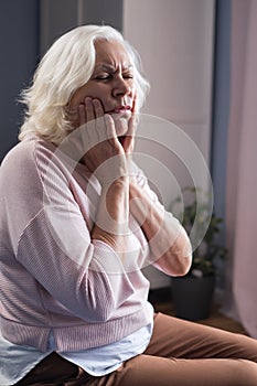Woman touching mouth with hand with painful expression because of toothache