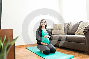 Woman Touching Pregnant Belly On Exercise Mat