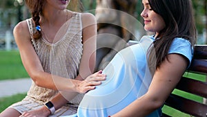 Woman touching pregnant friend`s belly close up