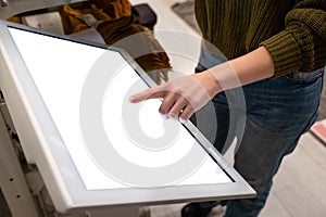 Woman touching the screen of self service device in the store.