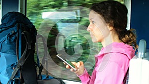 Woman tourist with backpack photographs the view from the window on the smartphone in the train, traveling in the car