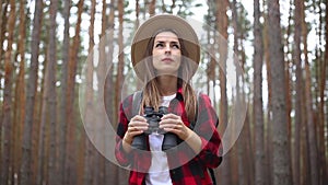 Woman tourist with binoculars looks around in the forest. Concept hike, tourism.