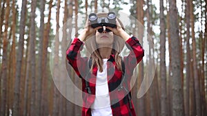 Woman tourist with binoculars looks around in the forest. Concept hike, tourism.