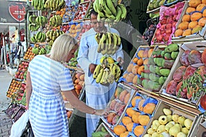 Woman tourist buying fruits at street seller. mangoes, pomegranates, guava