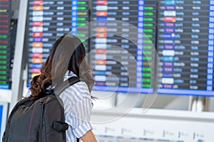 Woman tourist checking flight time table on board in airport. With copy space