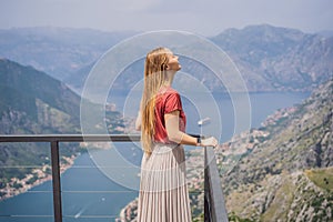 Woman tourist enjoys the view of Kotor. Montenegro. Bay of Kotor, Gulf of Kotor, Boka Kotorska and walled old city