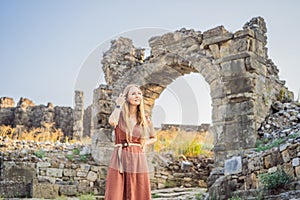 Woman tourist explores Aspendos Ancient City. Aspendos acropolis city ruins, cisterns, aqueducts and old temple