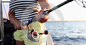 Woman tourist fisherman holds fishing rod and spins reel luring fish