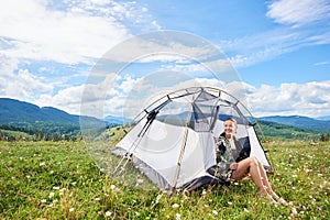 Woman tourist hiking in mountain trail, enjoying summer sunny morning in mountains near tent