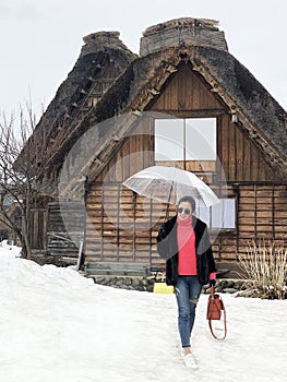 Woman tourist holding transparent umbrella in the winter and snow is falling at Shirakawago village at Gifu, Japan