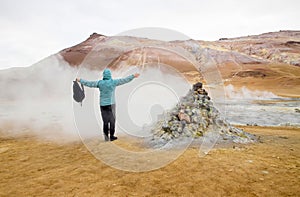 Woman tourist in Hverir , Iceland geothermal area at the Namafjall volcanic mountain. Standing in natural steam vent.