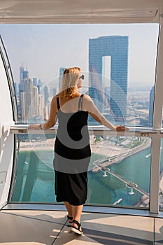 Woman tourist inside Ferris wheel cabin of Dubai Eye Ain  - One of the largest in the World, located on Bluewaters island. Top