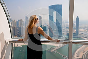 Woman tourist inside Ferris wheel cabin of Dubai Eye Ain  - One of the largest in the World, located on Bluewaters island. Top