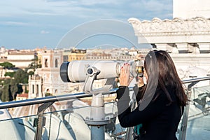 Woman tourist is looking through binoculars on city