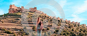 Woman tourist looking at impressive castle in Castile and Leon- Gormaz, Soria province