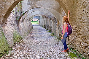 Woman tourist looking throw an archway with multiple arches, paved with cobblestone, in Biertan fortified church, Transylvania