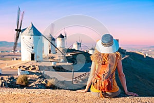 Woman tourist looking at windmills with castle, Consuegra