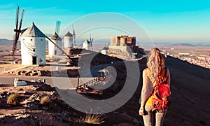 Woman tourist looking at windmills with castle, Consuegra