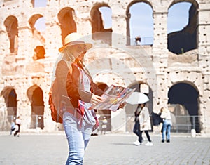 Woman tourist with map at Rome in front of Colosseum, Italy