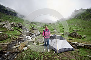 Woman tourist near tent in valley of Romanian mountains