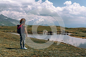 A woman tourist, next to a high mountain lake in which cows graze. Sunny day, trips. Koruldi Lakes, Mestia, Georgia. Copy space